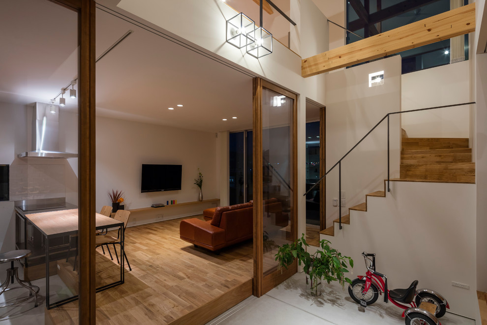 Offenes Modernes Wohnzimmer mit weißer Wandfarbe, braunem Holzboden und TV-Wand in Tokio