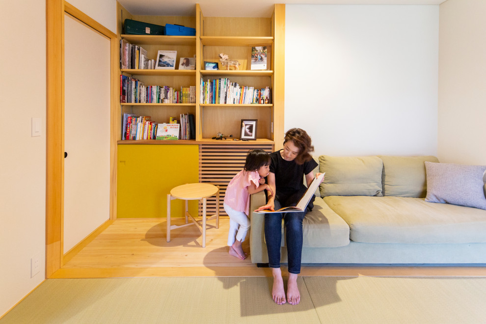 Immagine di un soggiorno etnico di medie dimensioni con libreria, pareti bianche, parquet chiaro e pavimento beige