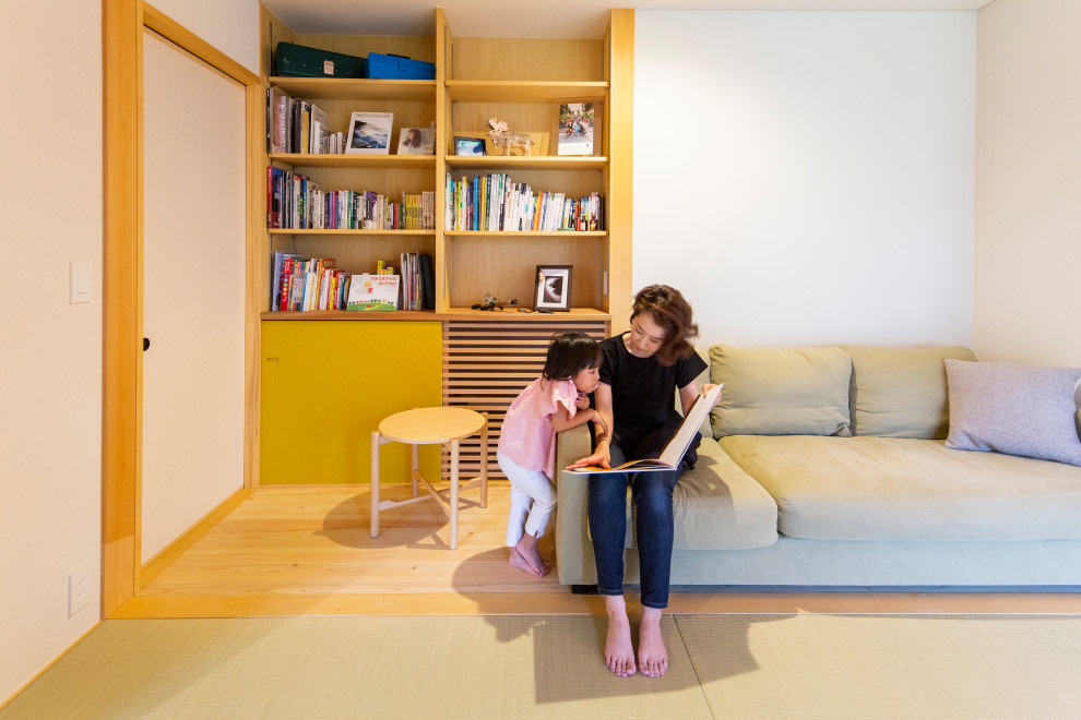 Réalisation d'un salon asiatique de taille moyenne avec une bibliothèque ou un coin lecture, un mur blanc, parquet clair et un sol beige.