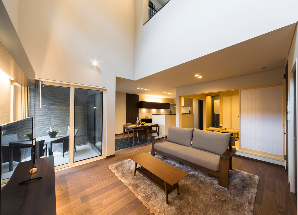 Ejemplo de salón abierto de estilo zen con paredes blancas, suelo de madera oscura, televisor independiente y suelo marrón