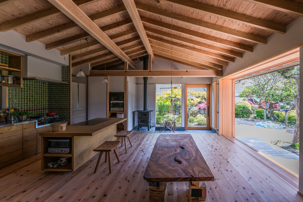 Cette photo montre un salon asiatique ouvert avec un mur blanc, un sol en bois brun, un poêle à bois, un manteau de cheminée en béton, un téléviseur fixé au mur et un sol marron.