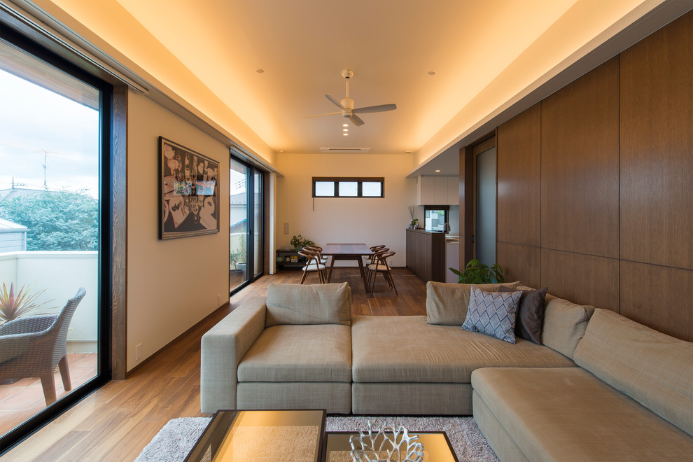 Diseño de salón abierto asiático con paredes blancas, suelo de madera en tonos medios y suelo marrón