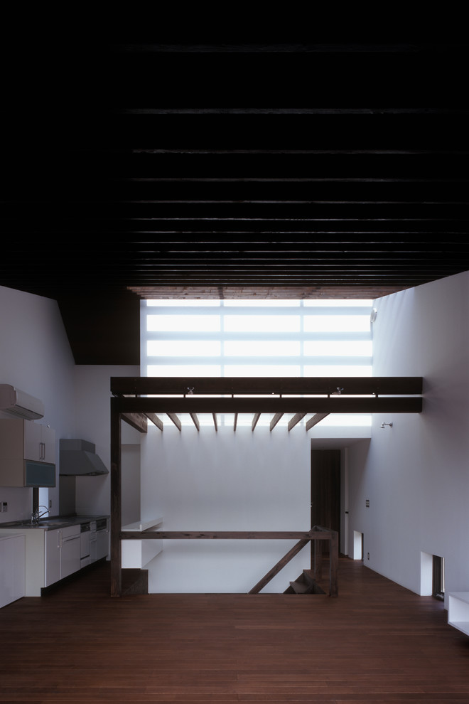 Imagen de salón de estilo zen con paredes blancas, suelo de madera oscura, televisor colgado en la pared y suelo marrón