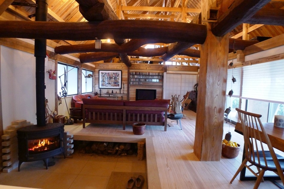 Aménagement d'un grand salon asiatique ouvert avec un mur blanc, parquet clair, un poêle à bois, un manteau de cheminée en carrelage et un sol blanc.