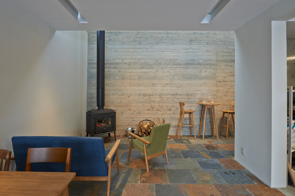 This is an example of a world-inspired open plan living room with white walls, multi-coloured floors and a wood burning stove.