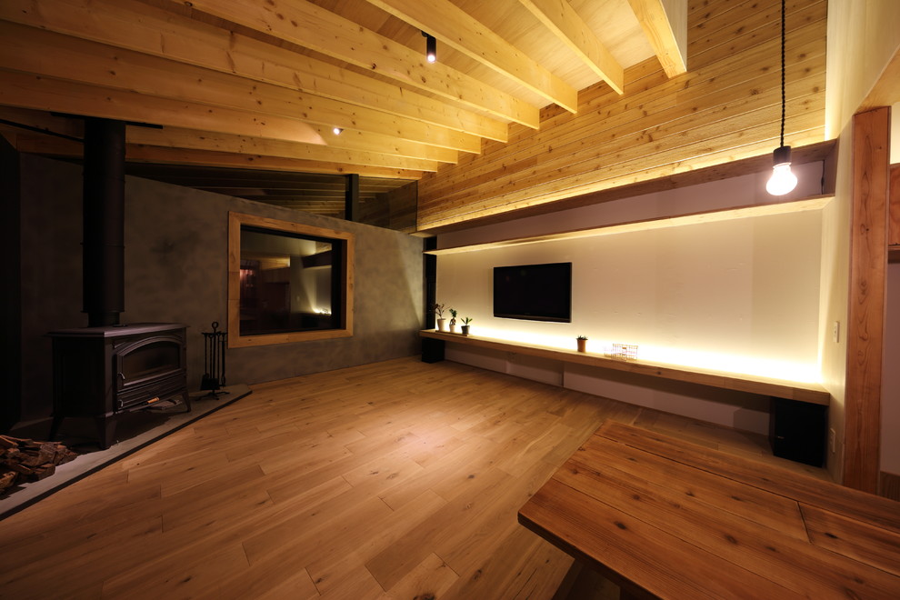 Inspiration pour un salon design ouvert avec un mur blanc, un sol en bois brun, un poêle à bois, un manteau de cheminée en métal et un téléviseur fixé au mur.