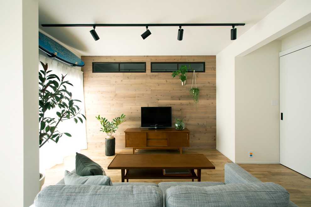 Ejemplo de salón nórdico sin chimenea con paredes blancas, suelo de madera clara y televisor independiente