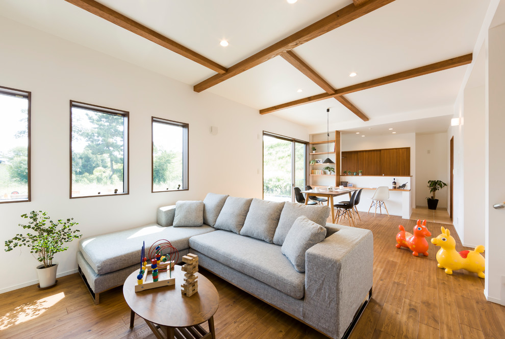 Imagen de salón abierto campestre con paredes blancas, suelo de madera en tonos medios y suelo marrón