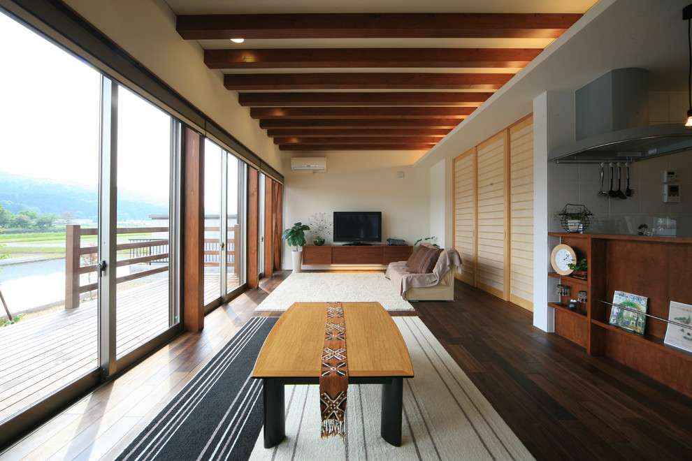 Immagine di un grande soggiorno etnico aperto con sala formale, pareti bianche, parquet scuro, TV autoportante e pavimento marrone