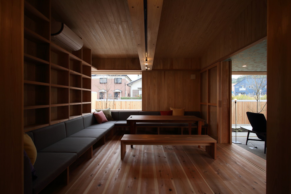 Cette image montre un salon nordique de taille moyenne et fermé avec une bibliothèque ou un coin lecture, un mur beige, parquet clair, un poêle à bois, un manteau de cheminée en béton, aucun téléviseur et un sol marron.