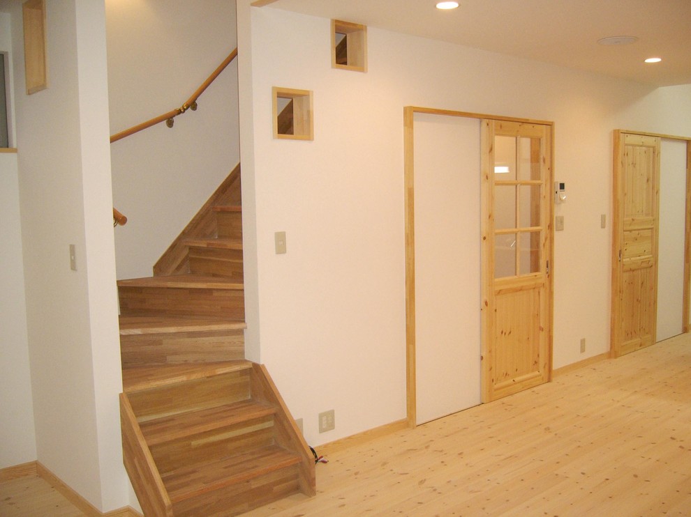 Cette image montre un petit salon nordique ouvert avec un mur blanc, parquet clair et un sol beige.