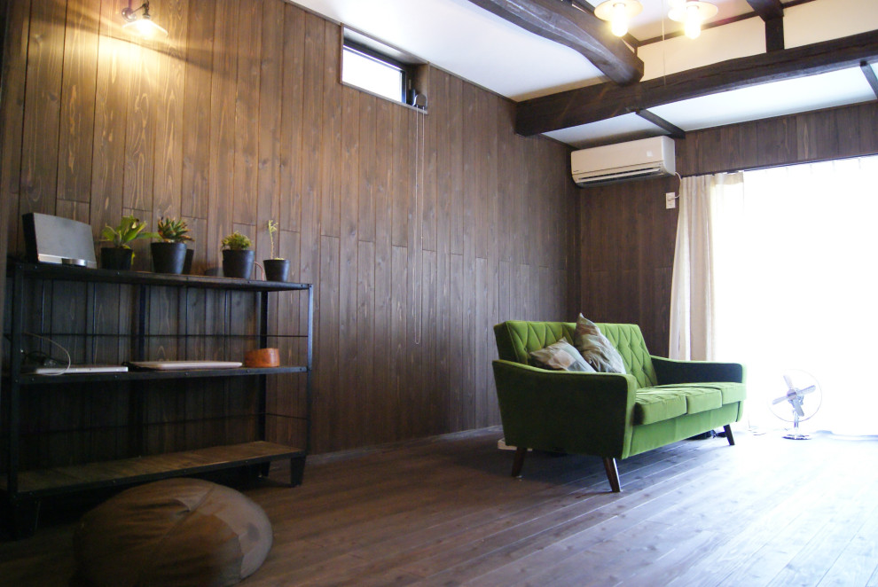 Diseño de salón abierto asiático pequeño sin chimenea con paredes marrones, suelo de madera oscura, televisor independiente, suelo marrón, vigas vistas y madera