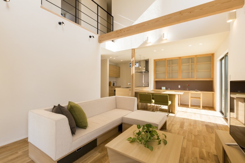 Modelo de salón abierto de estilo zen sin chimenea con paredes blancas, suelo de madera clara, televisor independiente y suelo marrón