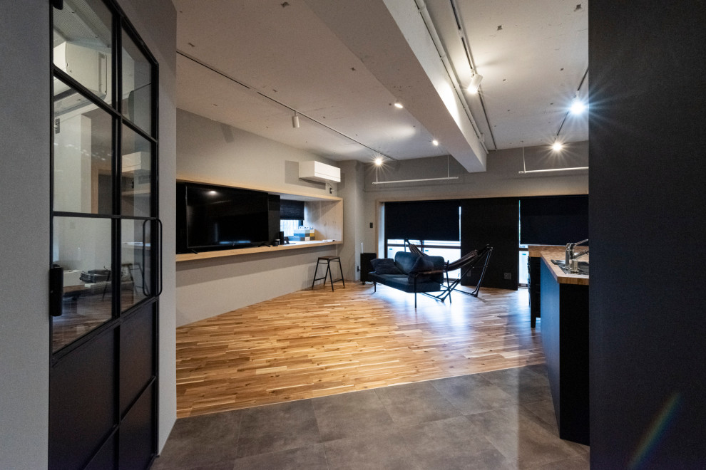 Diseño de salón para visitas abierto urbano de tamaño medio sin chimenea con paredes grises, televisor independiente y suelo marrón