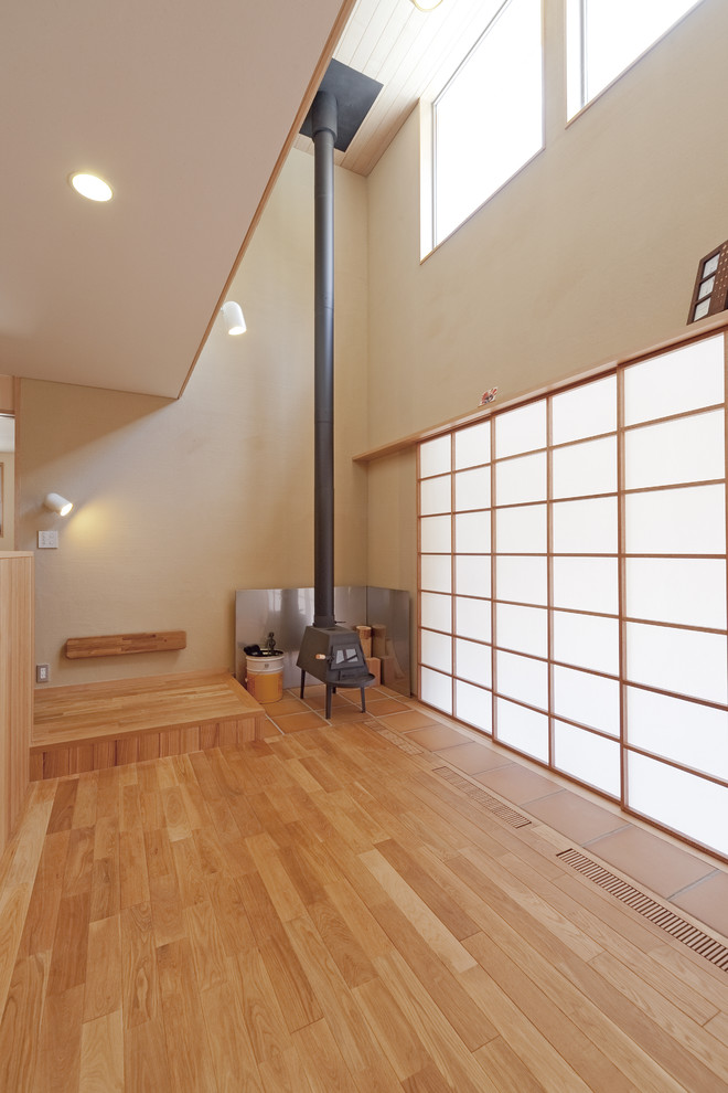 Modelo de salón abierto de estilo zen con paredes blancas, suelo de madera clara, chimenea de esquina, marco de chimenea de baldosas y/o azulejos y televisor independiente