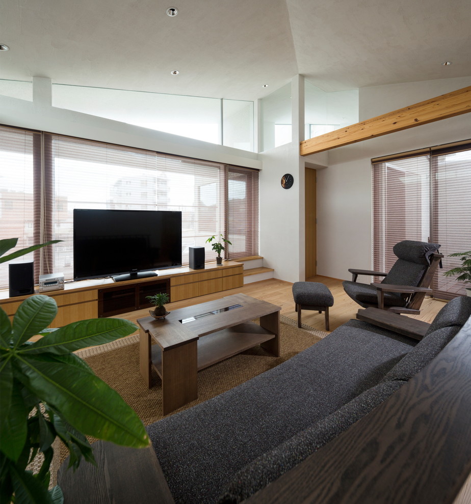 Cette photo montre un salon tendance avec un mur blanc, un sol en bois brun, un téléviseur indépendant et un sol marron.