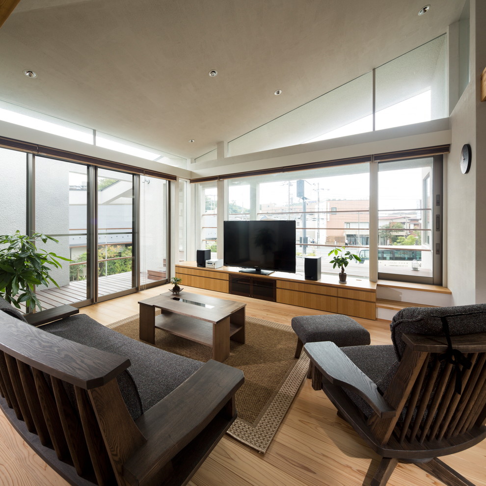 Cette image montre un salon asiatique avec un mur blanc, un sol en bois brun, un téléviseur indépendant et un sol marron.