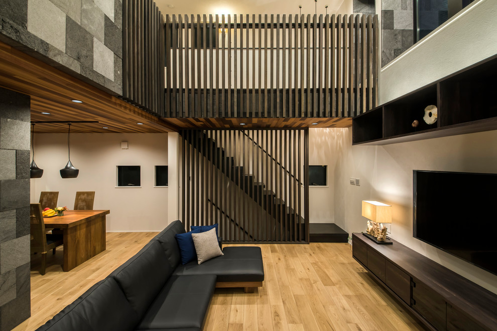 Immagine di un soggiorno etnico aperto con pareti bianche, pavimento in legno massello medio, TV a parete e pavimento marrone