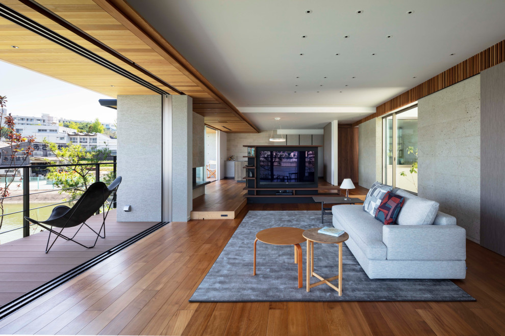 Idee per un soggiorno design aperto con pareti grigie, pavimento in legno massello medio e pavimento marrone