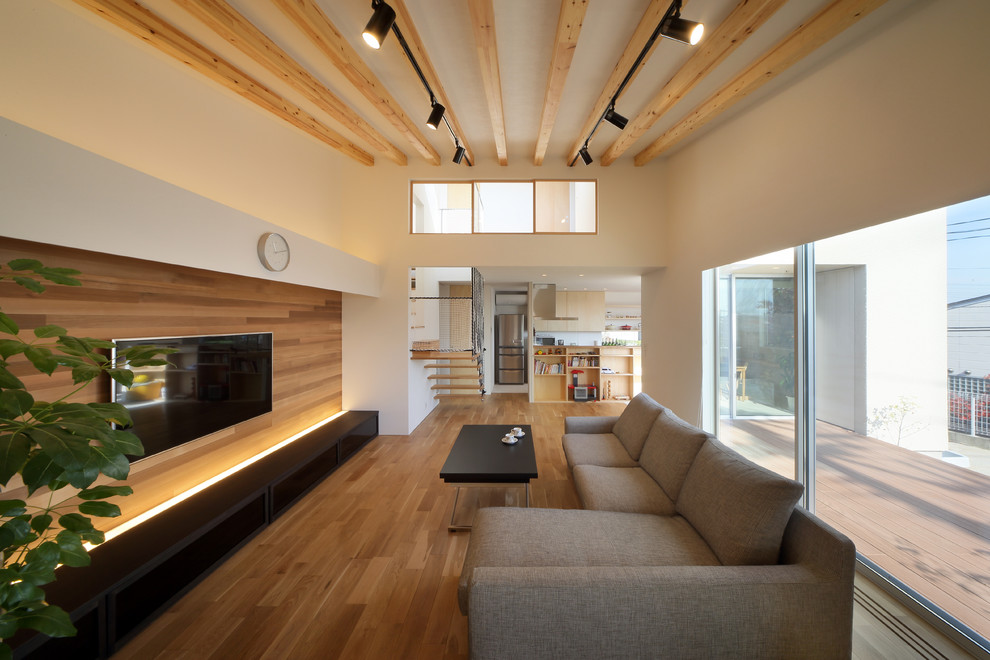 Immagine di un soggiorno etnico aperto con pareti bianche, pavimento in legno massello medio, TV a parete e pavimento marrone