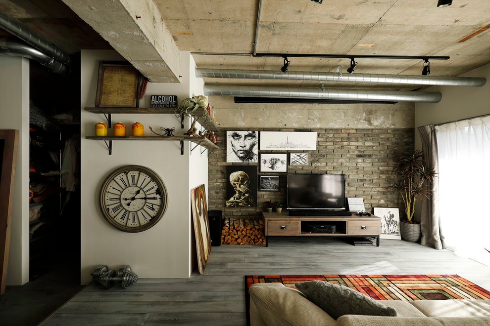 This is an example of an industrial living room with grey walls, medium hardwood flooring, a freestanding tv and grey floors.