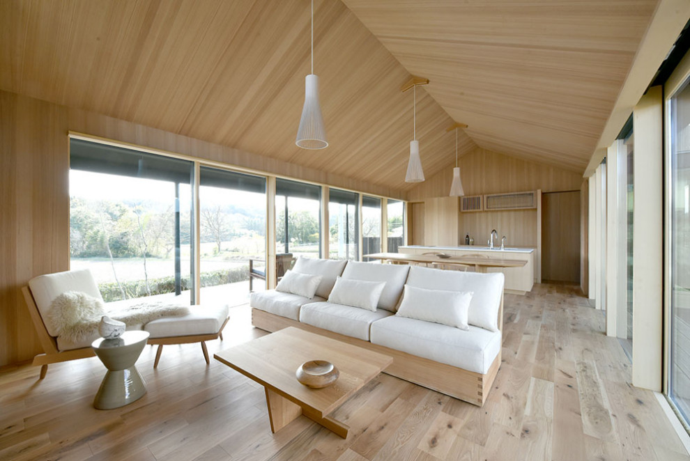 Modelo de salón para visitas abierto minimalista grande sin chimenea con paredes beige, suelo de madera clara, televisor colgado en la pared, suelo beige, madera y madera