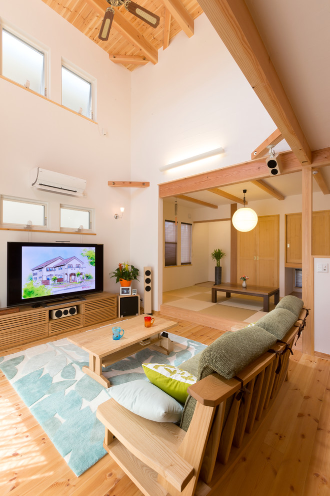 Idéer för orientaliska allrum med öppen planlösning, med vita väggar, mellanmörkt trägolv, en fristående TV och brunt golv
