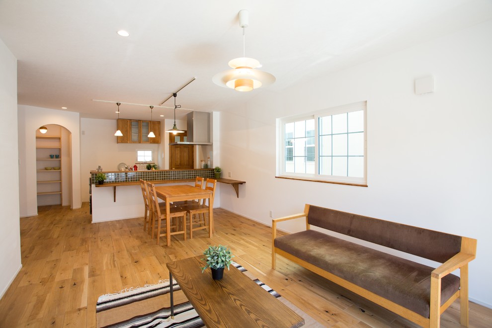 Mittelgroßes, Offenes Landhaus Wohnzimmer mit weißer Wandfarbe, braunem Holzboden und braunem Boden in Sonstige