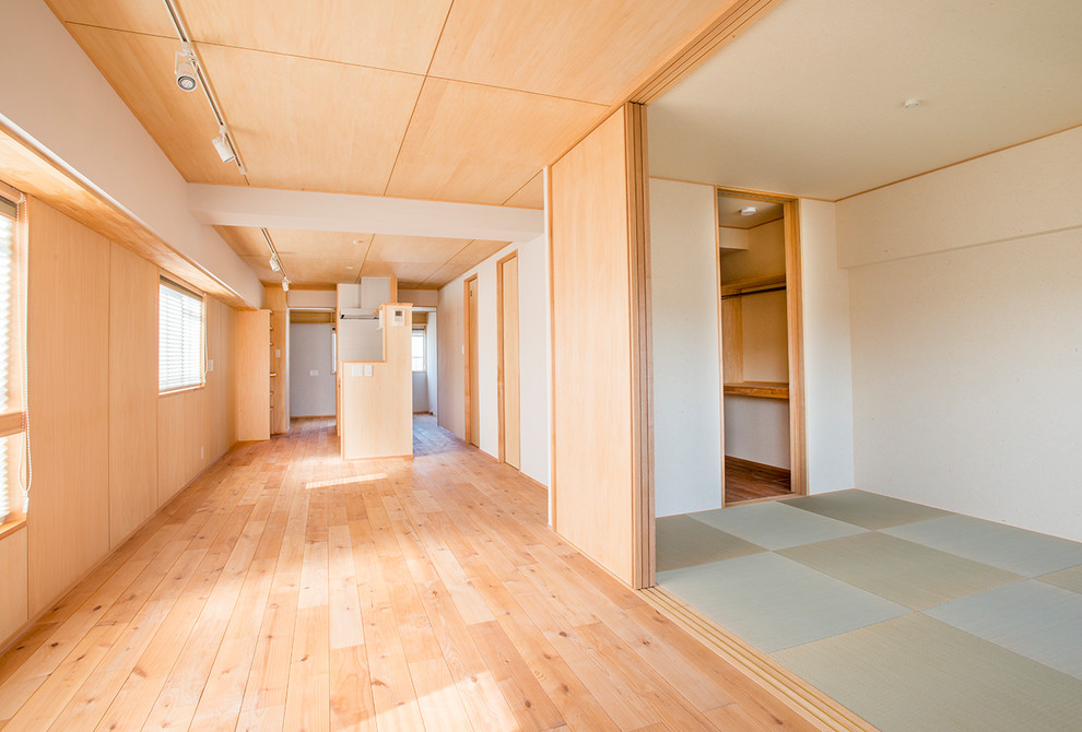 Diseño de salón abierto asiático de tamaño medio con paredes blancas, suelo de madera en tonos medios y suelo beige