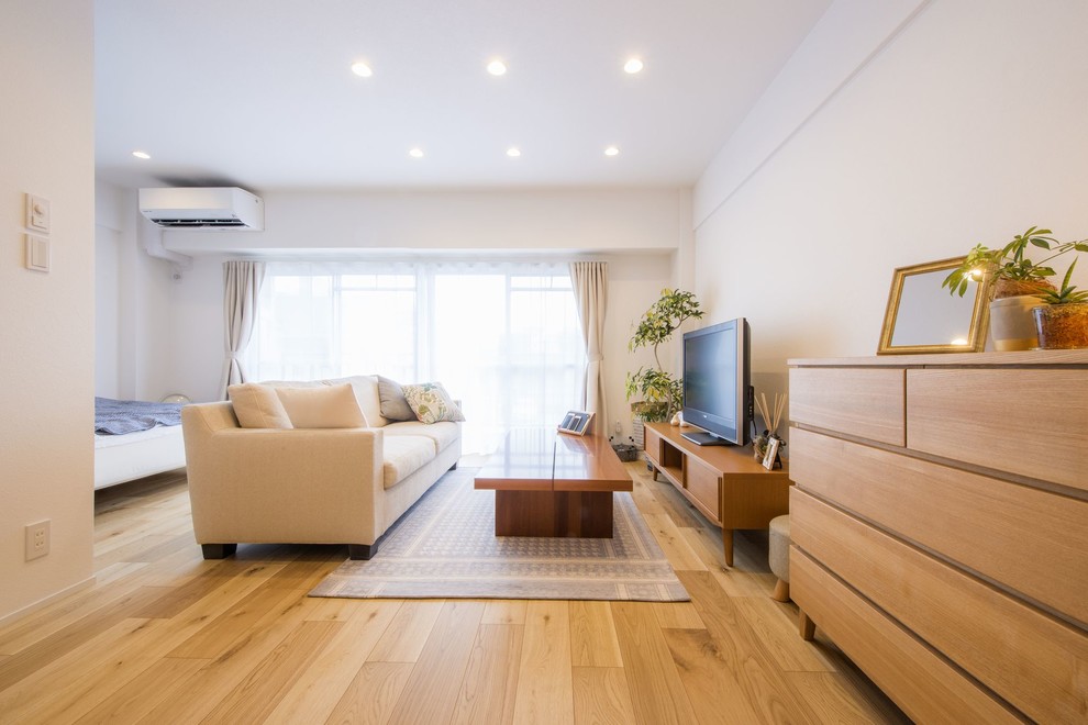 Idee per un soggiorno nordico aperto con pareti bianche, pavimento in legno massello medio, TV autoportante e pavimento marrone