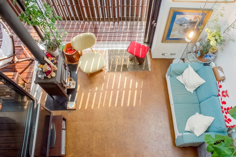 Immagine di un soggiorno minimalista di medie dimensioni e aperto con pareti bianche, pavimento in sughero, stufa a legna, TV autoportante e pavimento marrone