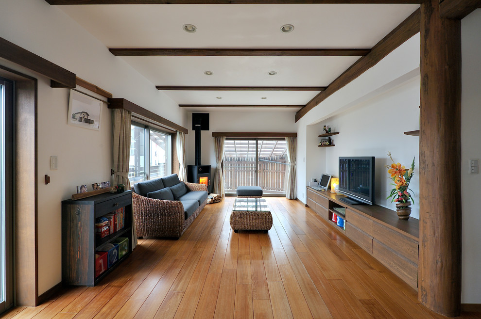 Idéer för orientaliska vardagsrum, med vita väggar, mellanmörkt trägolv, en fristående TV och brunt golv