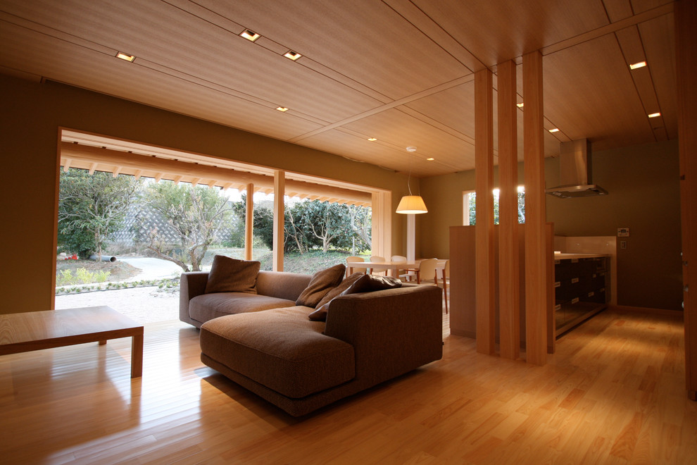Diseño de salón abierto asiático pequeño sin chimenea con paredes beige, suelo de madera clara y televisor independiente