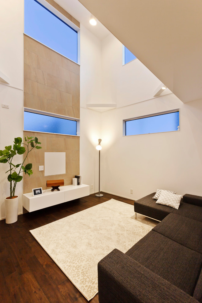 Imagen de salón nórdico con paredes blancas, suelo de madera oscura, televisor colgado en la pared y suelo marrón
