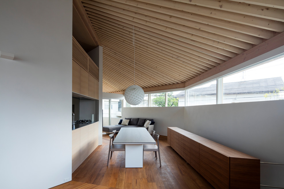 This is an example of a large modern living room in Kobe with white walls, plywood flooring, a wall mounted tv and brown floors.
