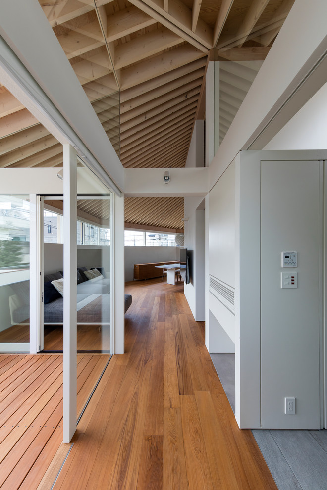 Großes Modernes Wohnzimmer ohne Kamin mit weißer Wandfarbe, braunem Boden, Sperrholzboden und TV-Wand in Kobe