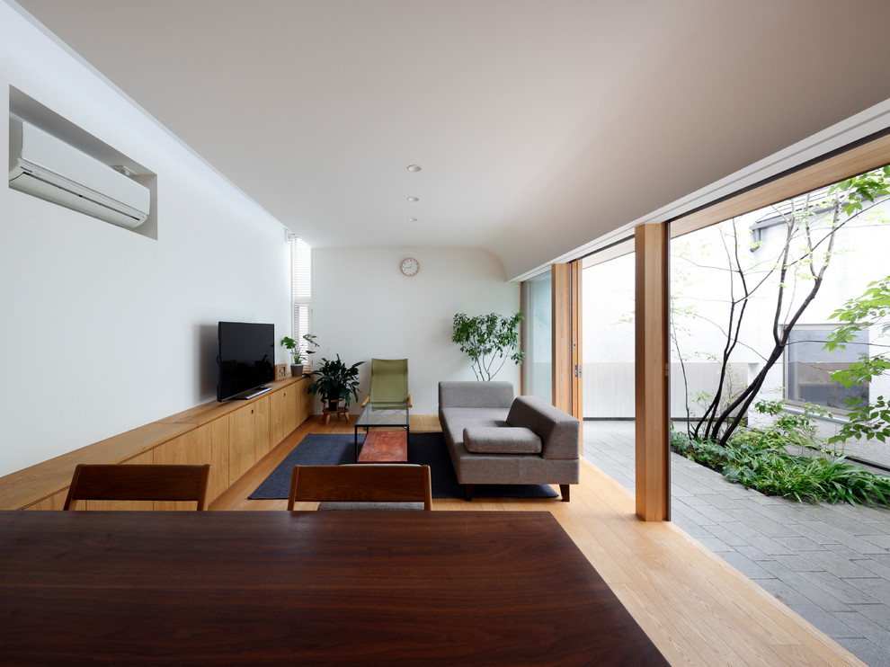 Immagine di un soggiorno minimalista aperto con pareti bianche, parquet chiaro, TV autoportante e pavimento beige