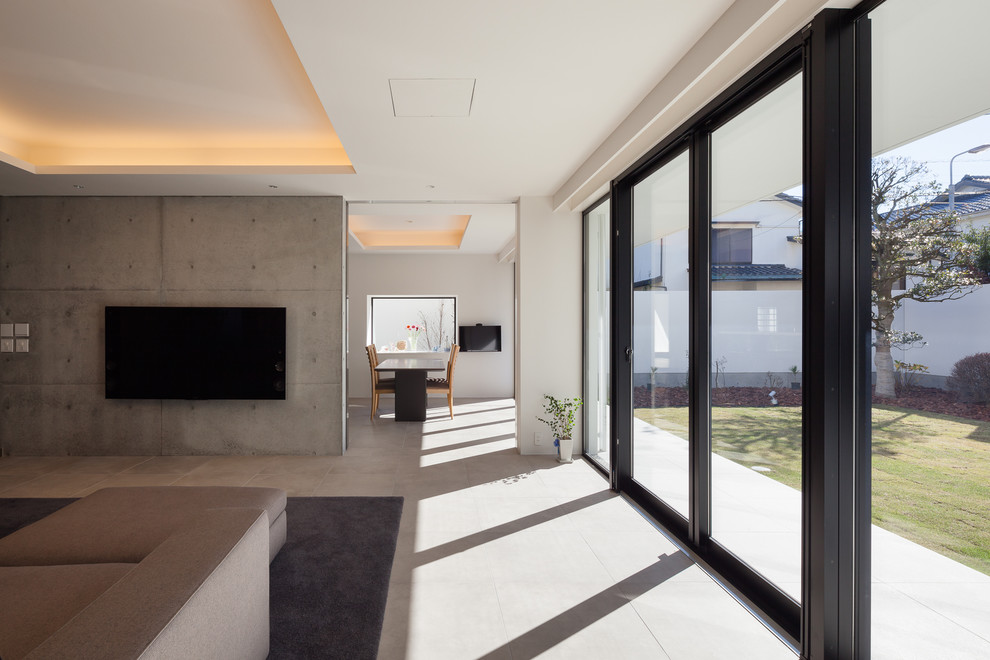 Пример оригинального дизайна: открытая гостиная комната в стиле модернизм с серыми стенами и телевизором на стене
