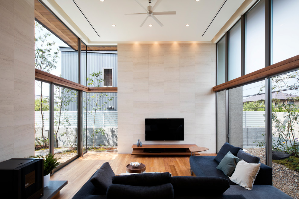 Diseño de salón minimalista con paredes beige, suelo de madera en tonos medios, televisor colgado en la pared y suelo marrón