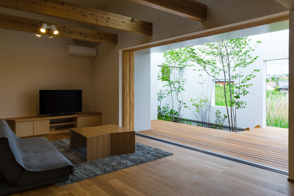 Ispirazione per un soggiorno minimalista con pareti bianche, pavimento in legno massello medio, TV autoportante e pavimento marrone