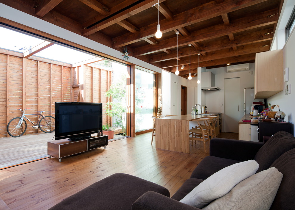 Offenes Modernes Wohnzimmer mit weißer Wandfarbe, braunem Holzboden, freistehendem TV und braunem Boden in Yokohama