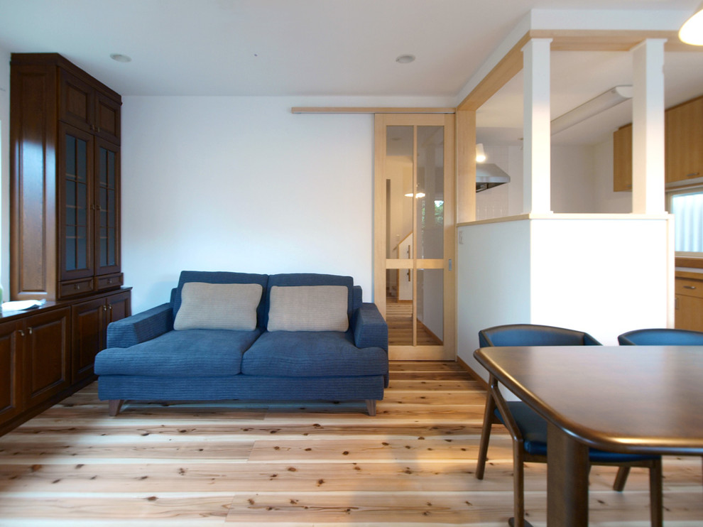 Minimalistisk inredning av ett vardagsrum, med vita väggar, ljust trägolv och beiget golv