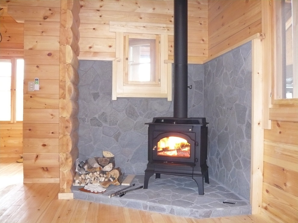Exemple d'un salon avec un poêle à bois et un manteau de cheminée en pierre.