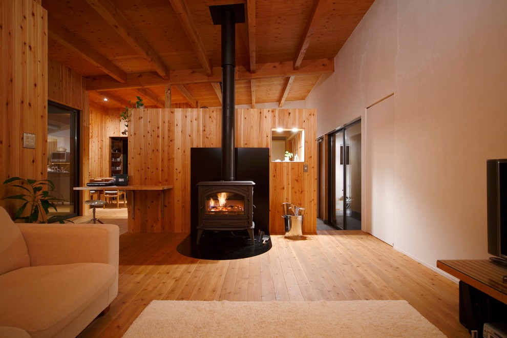 Photo of a world-inspired living room in Yokohama with white walls, medium hardwood flooring, a wood burning stove and brown floors.