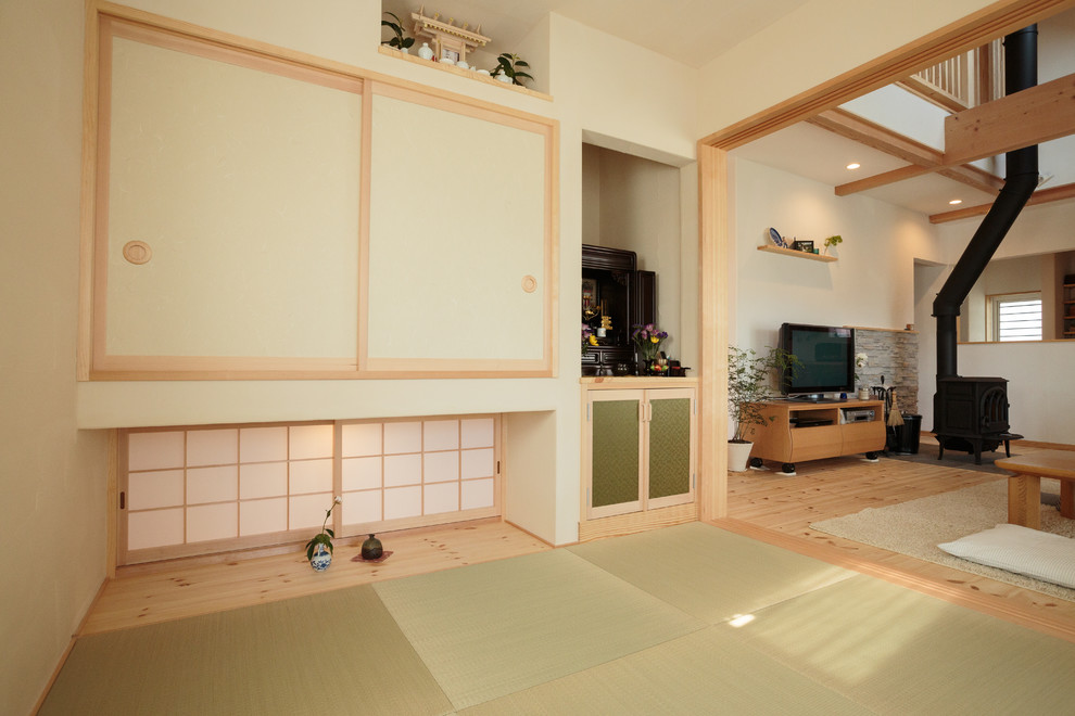 Réalisation d'un salon chalet avec un mur blanc, un sol de tatami, un poêle à bois et un téléviseur indépendant.