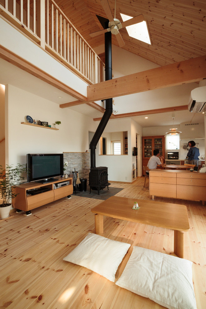 Imagen de salón abierto asiático con paredes blancas, suelo de madera clara, estufa de leña, televisor independiente y suelo marrón