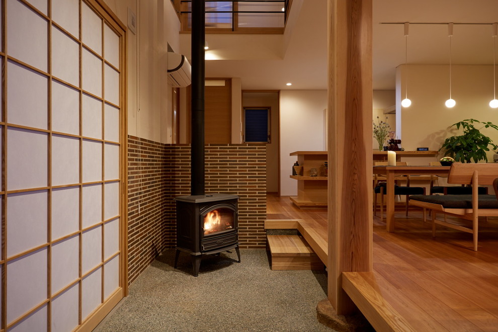 Offenes Asiatisches Wohnzimmer mit weißer Wandfarbe, braunem Holzboden, Eckkamin und gefliester Kaminumrandung in Sonstige