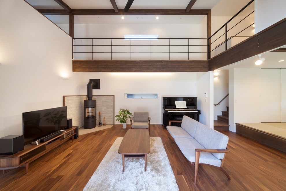 World-inspired living room in Other with white walls, a wood burning stove, a freestanding tv and brown floors.