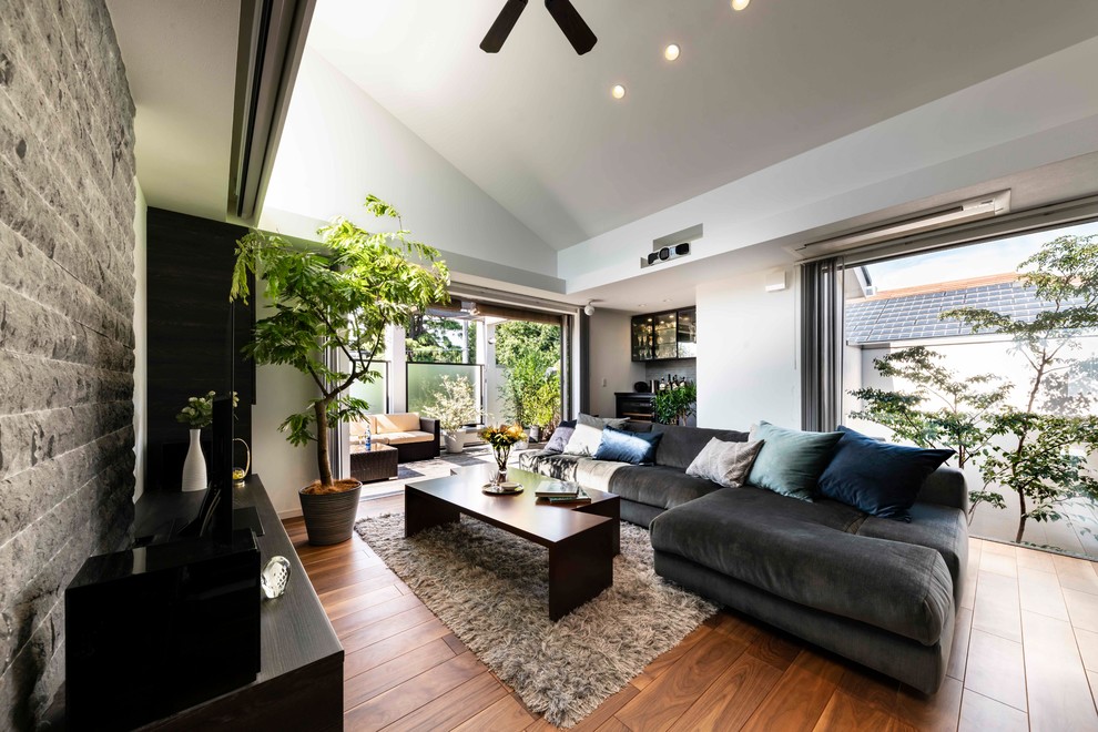 Large contemporary open plan living room in Yokohama with a home bar, white walls, a freestanding tv, medium hardwood flooring and brown floors.