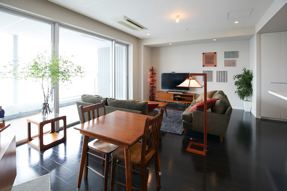 Immagine di un soggiorno etnico aperto con pareti bianche, TV autoportante e pavimento nero